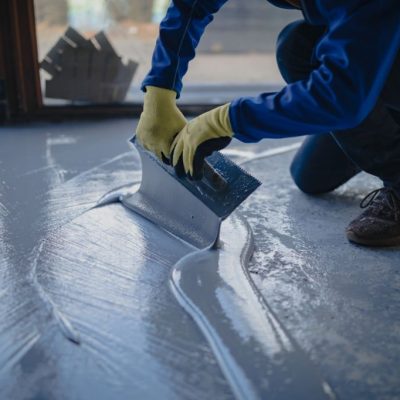 The worker applies gray epoxy resin to the new floor