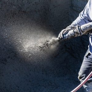 Pool Construction Worker Shooting Concrete, Shotcrete or Gunite Through Hose